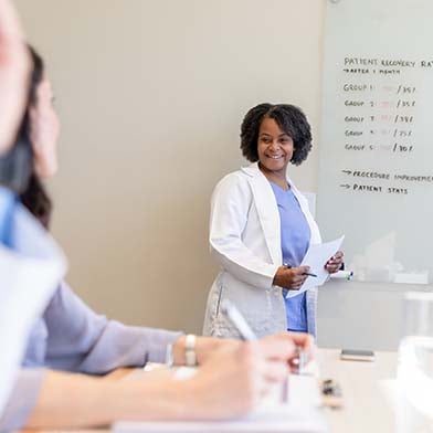 A person in a white coat standing in front of a whiteboard A person in a white coat standing in front of a whiteboard